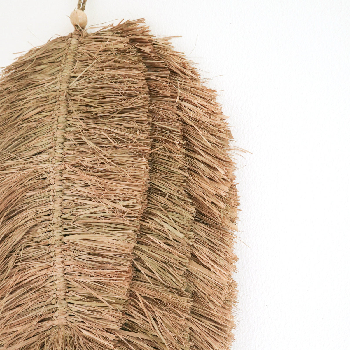 Detail der Raffia-Fransen, Flechtnaht und Holzperle an der Wanddeko TIPIN