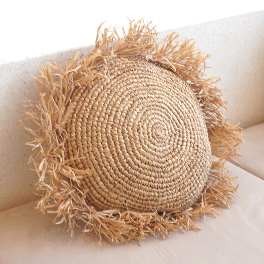 Soeji TARAKAN: rundes Raffia-Kissen mit Fransen auf heller Sitzfläche, schräge Nahansicht