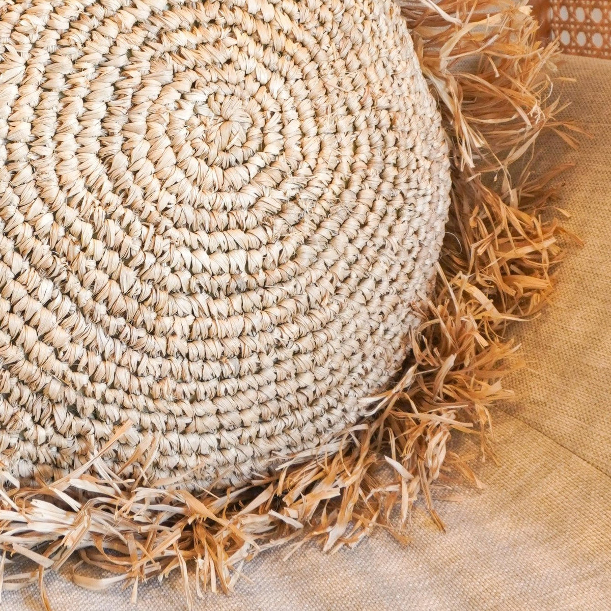 Detailaufnahme des geflochtenen Raffia-Kissens TARAKAN mit konzentrischer Struktur und Fransen