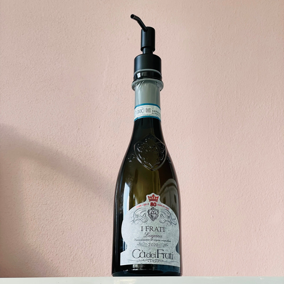 Cà dei Frati I Frati Lugana Flasche als Seifenspender mit schwarzem Pumpkopf vor heller Wand