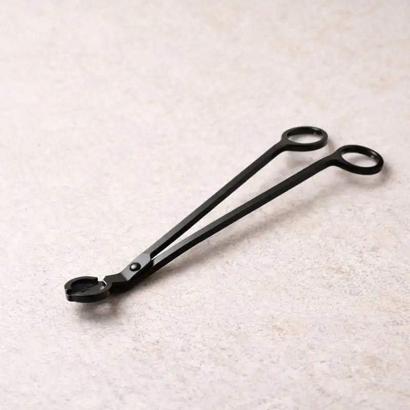 Hochwertige schwarze Dochtschere als stilvolles Kerzenzubehör, gezeigt im Einsatz und in ruhigen, wohnlichen Settings. Die elegante Kerzenschere ermöglicht das präzise Kürzen des Dochtes für ein sauberes, gleichmäßiges Abbrennen von Duftkerzen aus Naturwachs. Ideal für achtsame Rituale, gepflegte Wohnatmosphäre und als stilvolle Geschenkidee für Kerzenliebhaber.