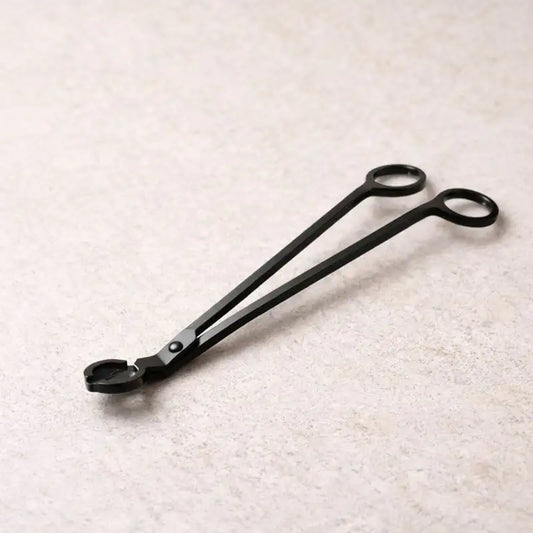 Hochwertige schwarze Dochtschere als stilvolles Kerzenzubehör, gezeigt im Einsatz und in ruhigen, wohnlichen Settings. Die elegante Kerzenschere ermöglicht das präzise Kürzen des Dochtes für ein sauberes, gleichmäßiges Abbrennen von Duftkerzen aus Naturwachs. Ideal für achtsame Rituale, gepflegte Wohnatmosphäre und als stilvolle Geschenkidee für Kerzenliebhaber.