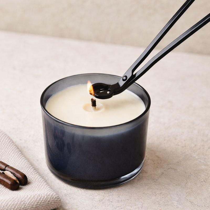 Hochwertige schwarze Dochtschere als stilvolles Kerzenzubehör, gezeigt im Einsatz und in ruhigen, wohnlichen Settings. Die elegante Kerzenschere ermöglicht das präzise Kürzen des Dochtes für ein sauberes, gleichmäßiges Abbrennen von Duftkerzen aus Naturwachs. Ideal für achtsame Rituale, gepflegte Wohnatmosphäre und als stilvolle Geschenkidee für Kerzenliebhaber.