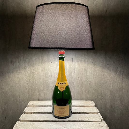 Krug Grande Cuvée Champagnerflasche mit dunklem Lampenschirm auf rustikalem Holztisch